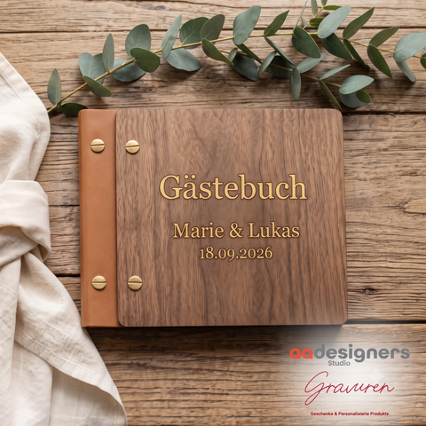 Holz-Gästebuch mit gravierten Namen Marie und Lukas und Hochzeitsdatum auf einem Holztisch