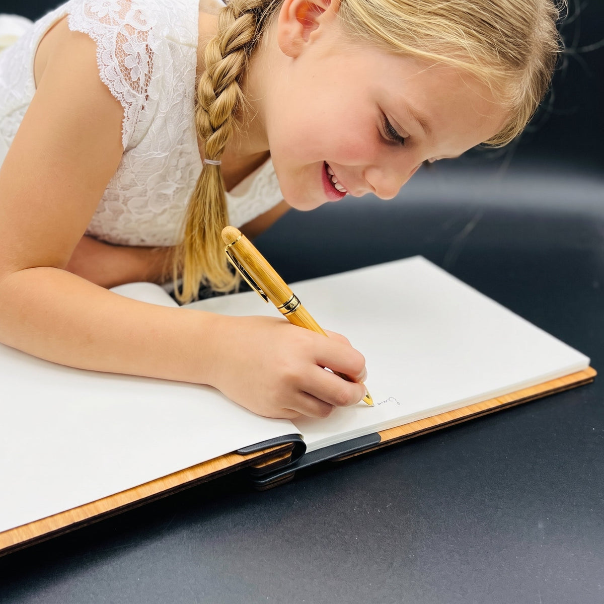 Kind schreibt mit einem Holzstift in ein aufgeschlagenes Notizbuch