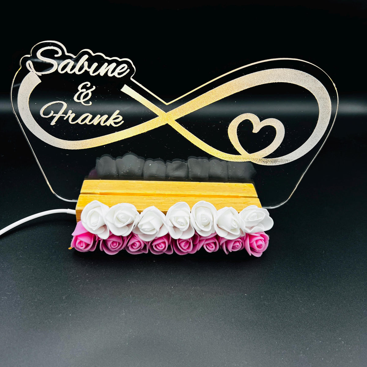 Personalisierte Unendlichkeitslampe mit Namen Sabine und Frank und weißen und rosa Rosen am Holzsockel